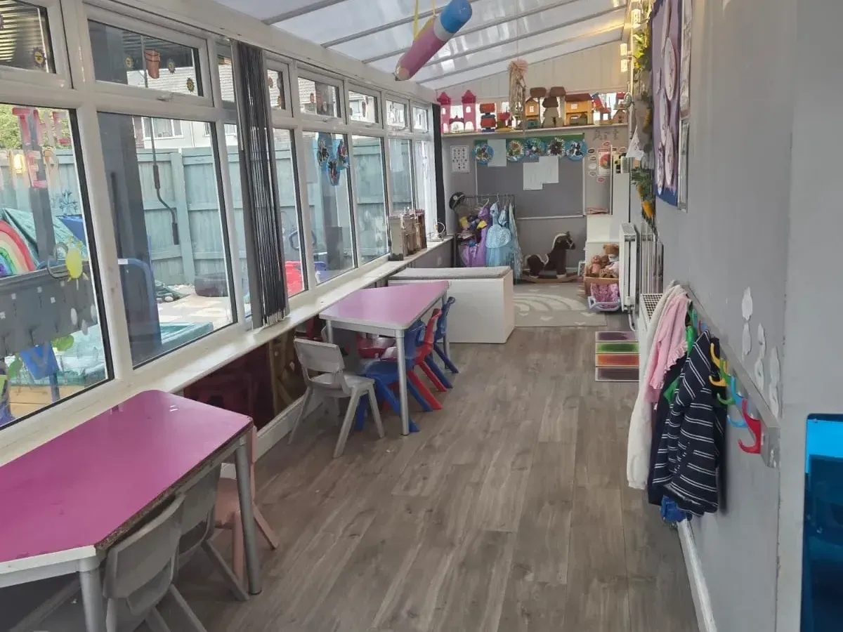 Bright conservatory room with children's tables, dressing up and a rocking horse at Ready Steady Go Childcare Worle
